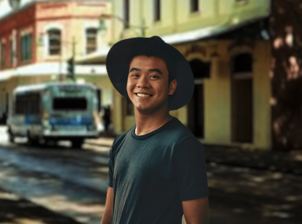 Asian young man in hat on sidewalk