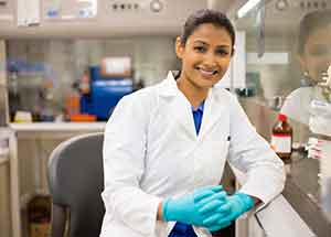 Lab tech student smiling next to lab equipment